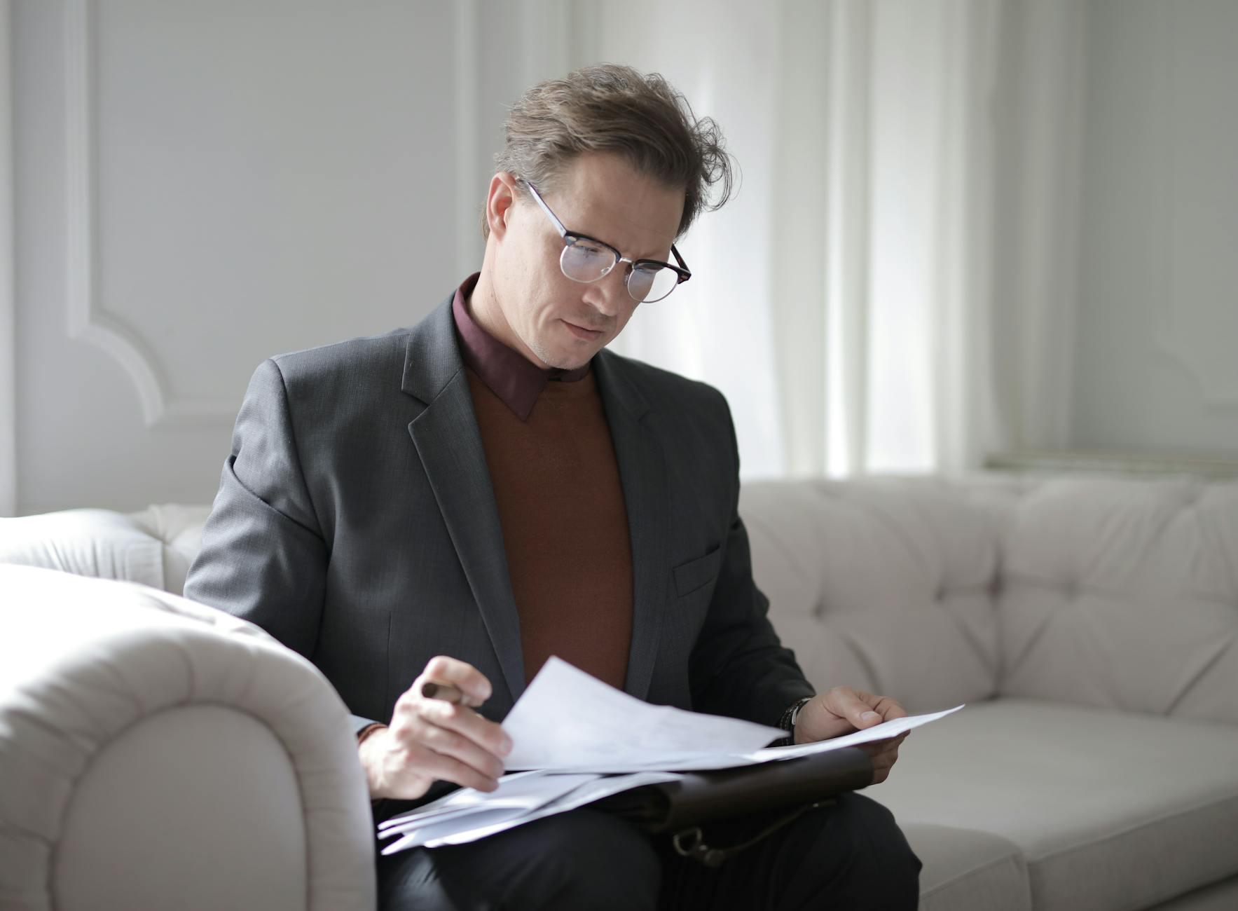 classy executive male reading papers on couch