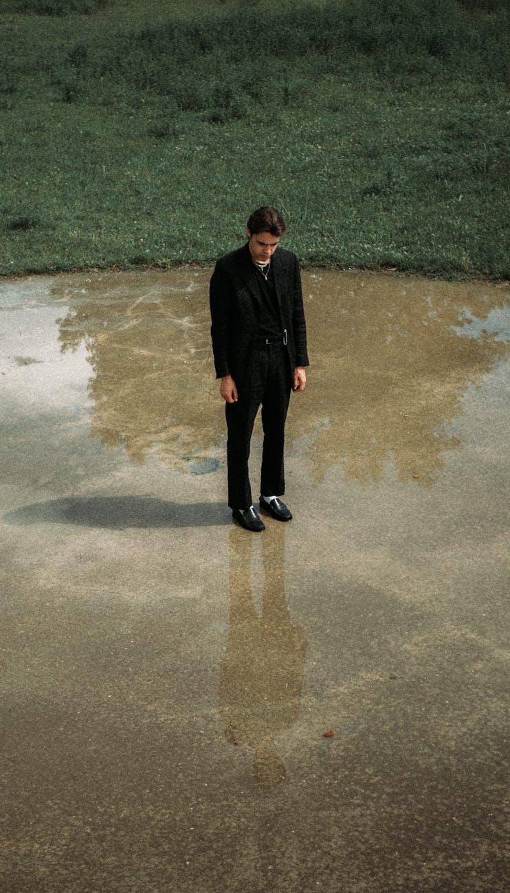 melancholic man in suit standing on wet ground in park