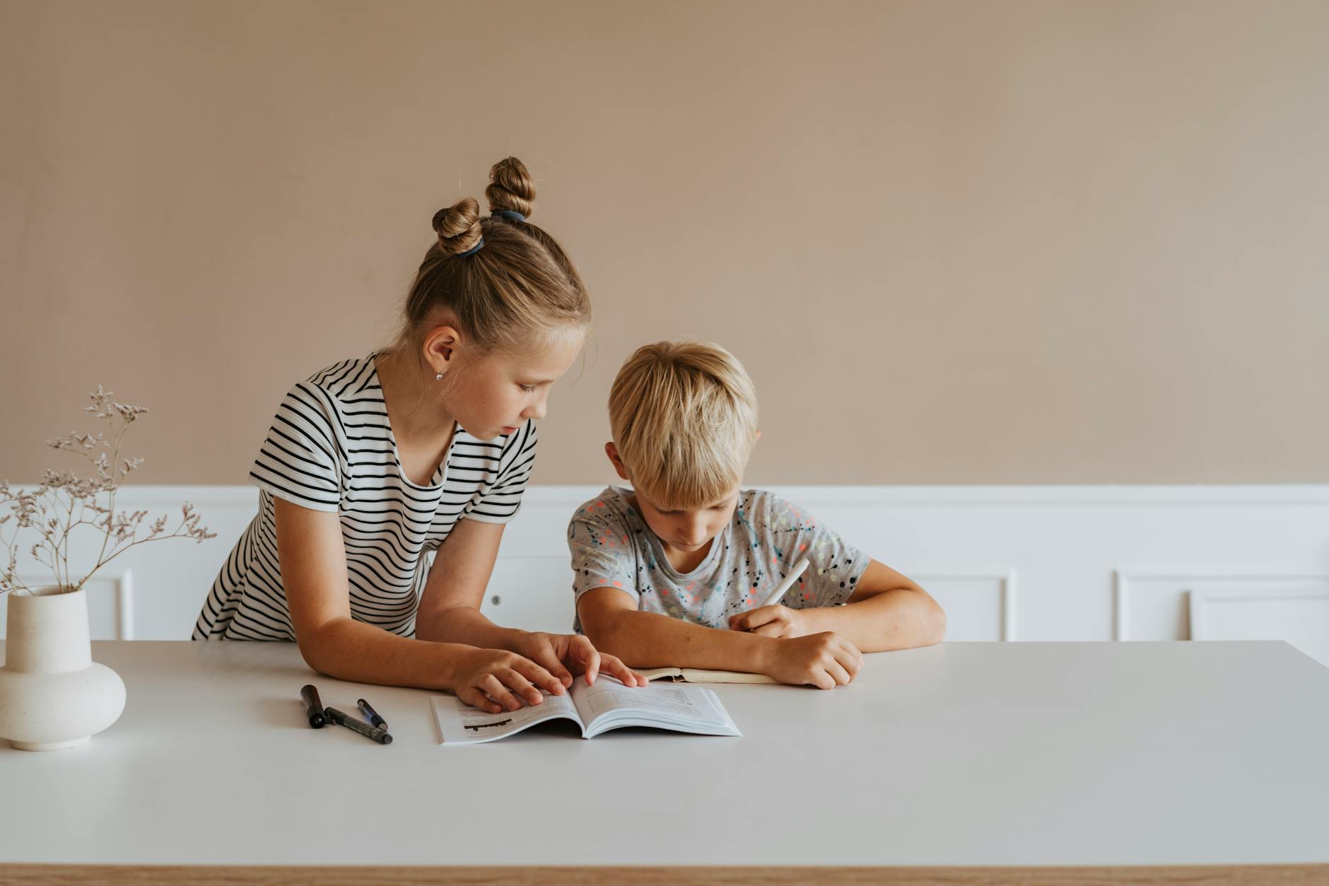 little girl helping her brother with homework