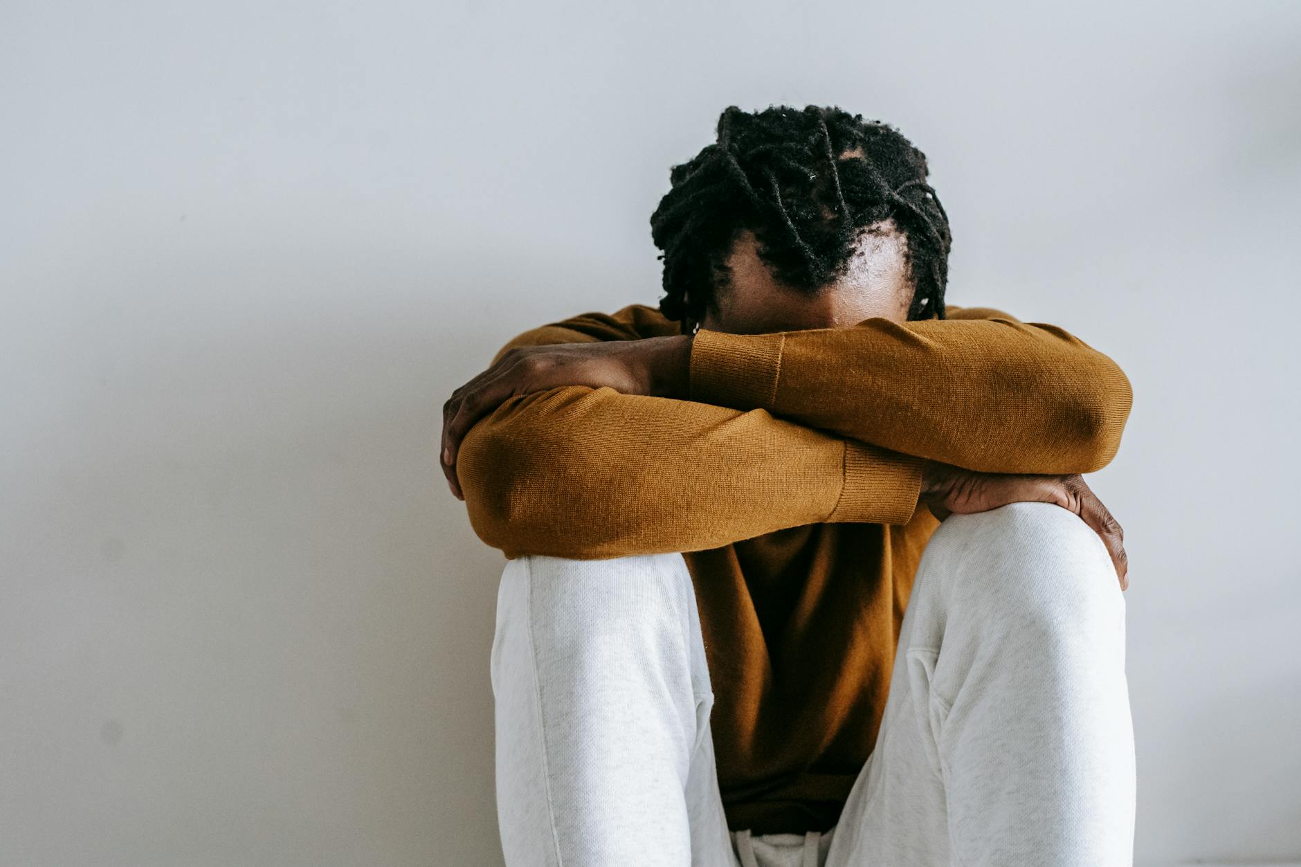 anonymous unhappy black man suffering on light background