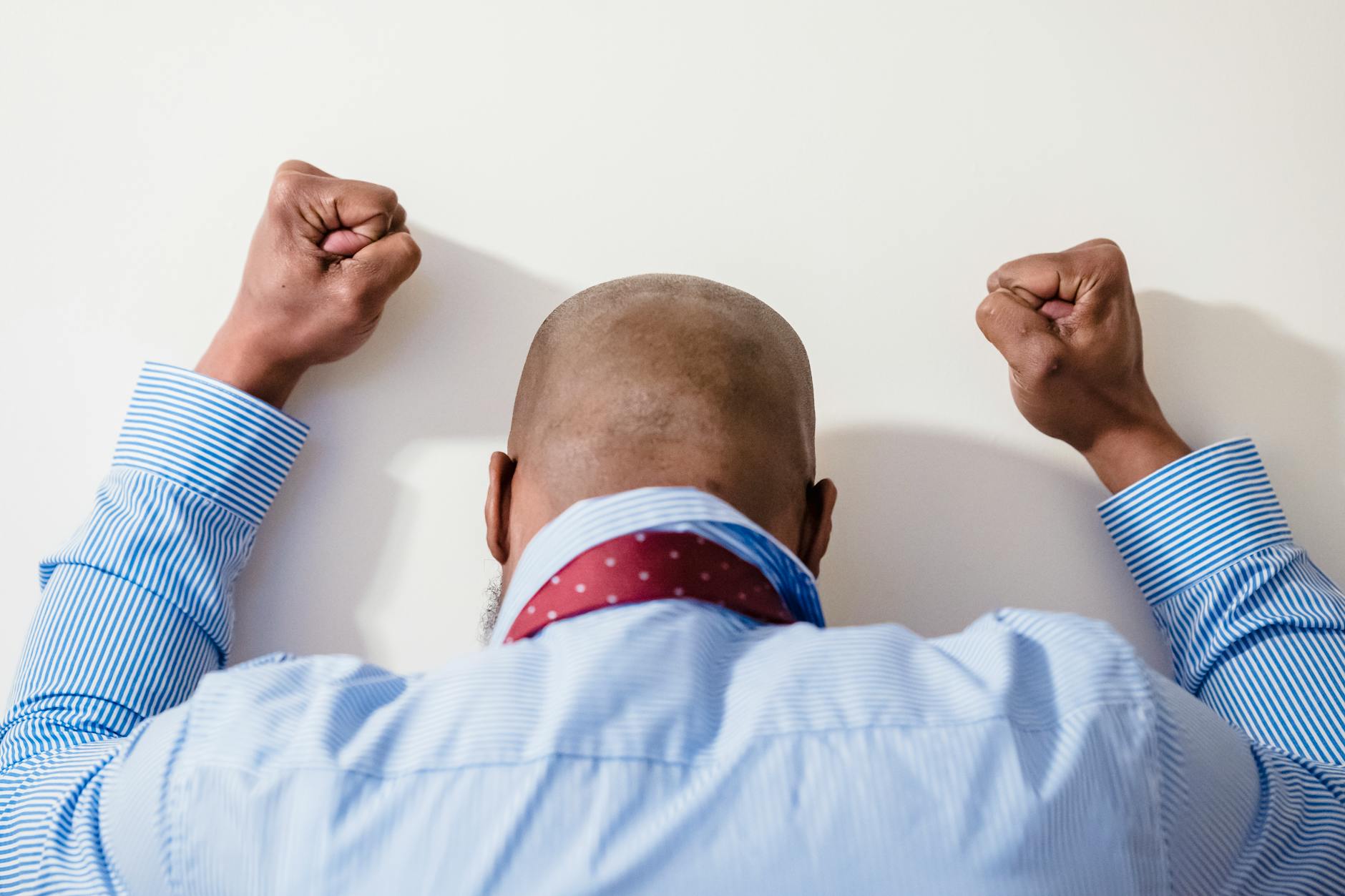 bald man facing white wall