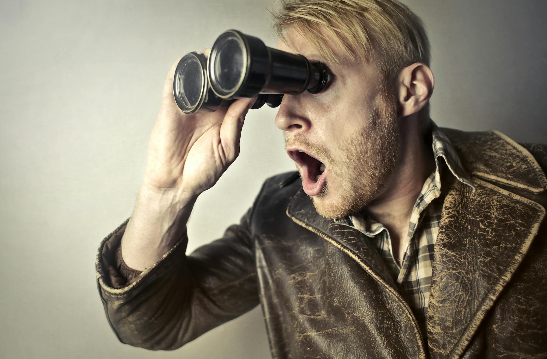 man in brown leather jacket using binoculars