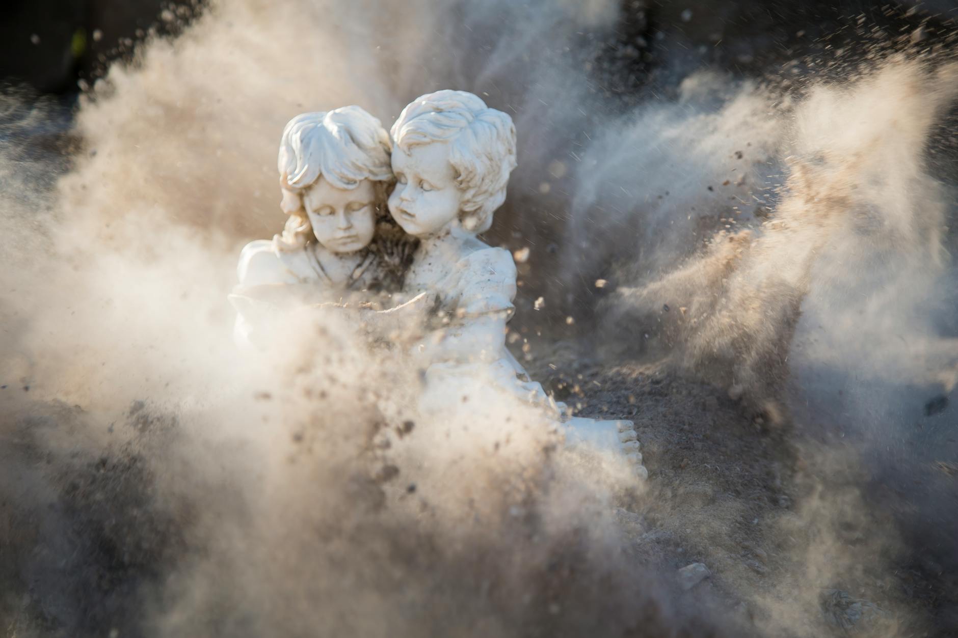 two white concrete statues covered by dust